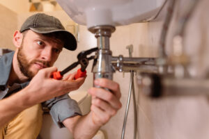 The plumber's careful approach highlights their professionalism and dedication to delivering high-quality service. They are equipped with the appropriate tools and materials, ensuring that the repair is done effectively and efficiently. The photo captures the importance of precision and attention to detail in plumbing work, as the plumber works to restore the functionality of the sink.