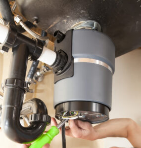 Man installing garbage disposal in home.